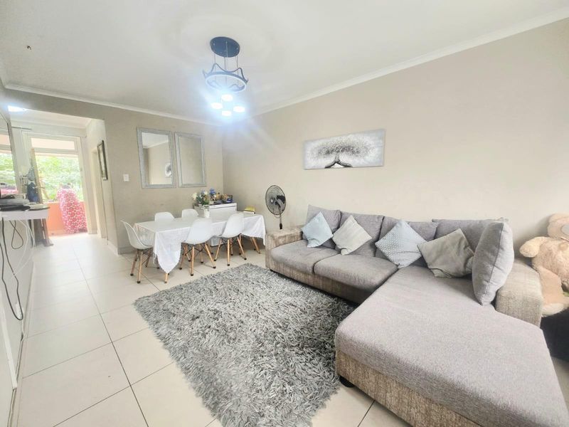 Open plan living and dining area featuring neutral wall tones and tiled flooring, providing a functional space with direct access to an outdoor area.