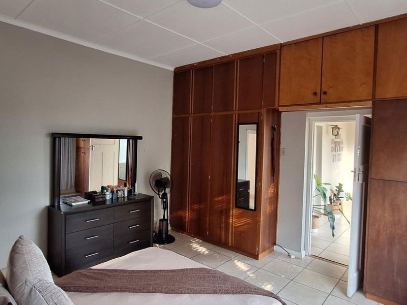 A bedroom featuring extensive built-in wooden cabinetry with overhead storage and tiled flooring, providing ample storage space.