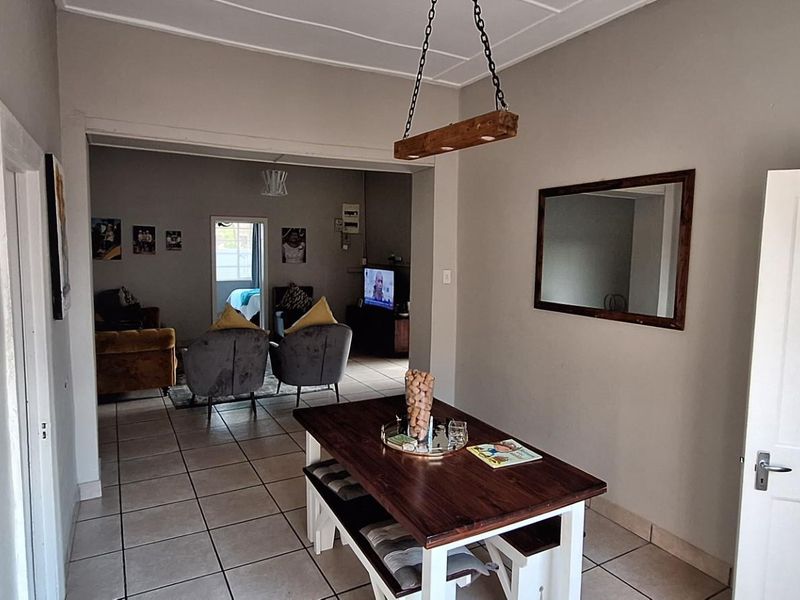 An open-plan dining area featuring tiled flooring and a pendant light fixture, leading into a connected living space.