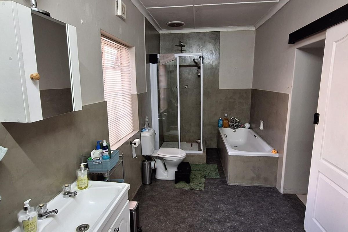 A functional bathroom featuring a built-in bathtub, separate glass-enclosed shower, vanity basin, and toilet with neutral wall finishes.