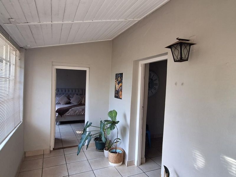 A sunroom or enclosed patio area featuring tiled flooring, a white timber-paneled ceiling, and large windows with fitted blinds.