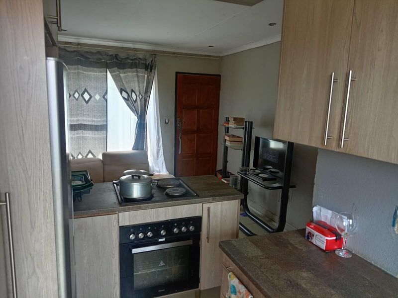 Compact kitchen featuring built-in cabinetry, a fitted oven and hob, and direct access to the living area.