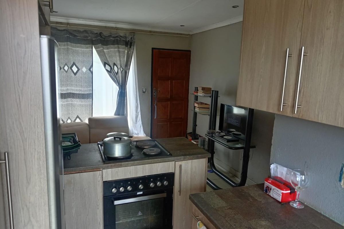 Compact kitchen featuring built-in cabinetry, a fitted oven and hob, and direct access to the living area.