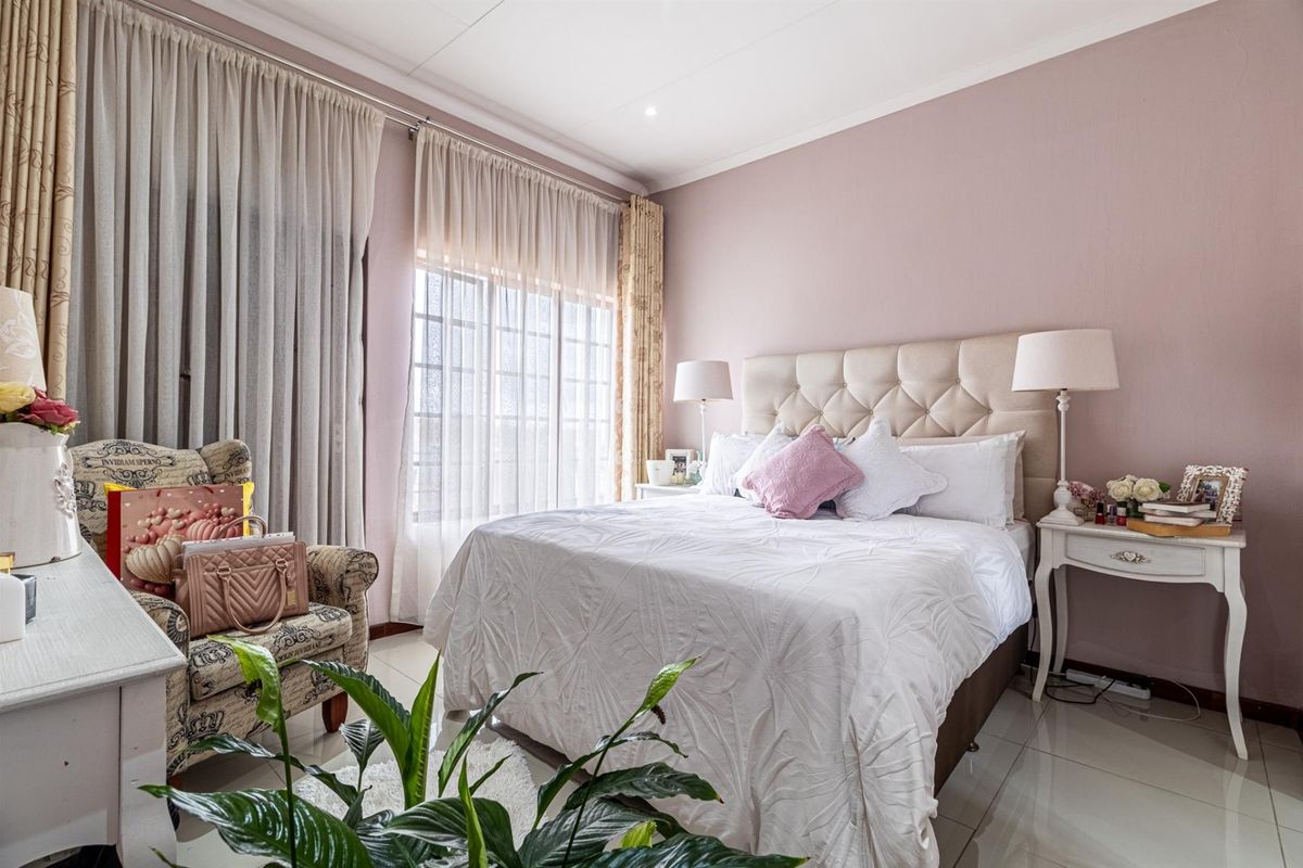 A well-maintained bedroom featuring tiled flooring, large windows with curtain tracks, and neutral wall finishes, providing a comfortable and bright living space.