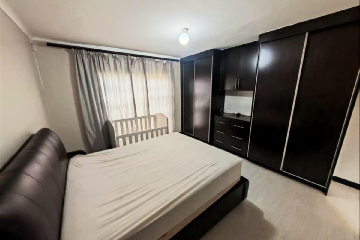 A bedroom featuring built-in dark wood cabinetry with integrated storage and drawers, providing ample space and a functional layout.