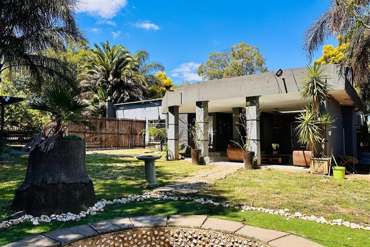 A spacious rear garden featuring a covered patio area, stone-bordered fire pit, and established landscaping, providing a private outdoor entertainment space.