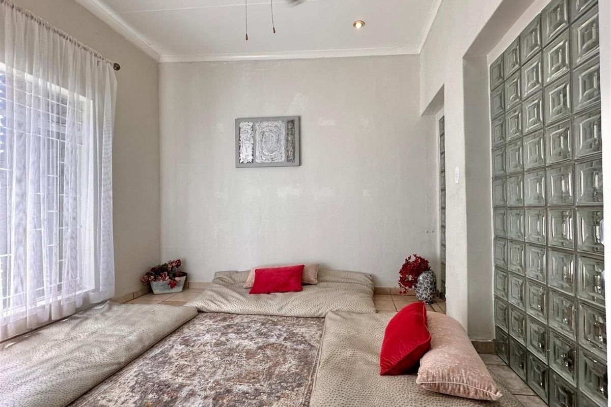 A living room featuring a glass block feature wall, tiled flooring, and a ceiling fan.