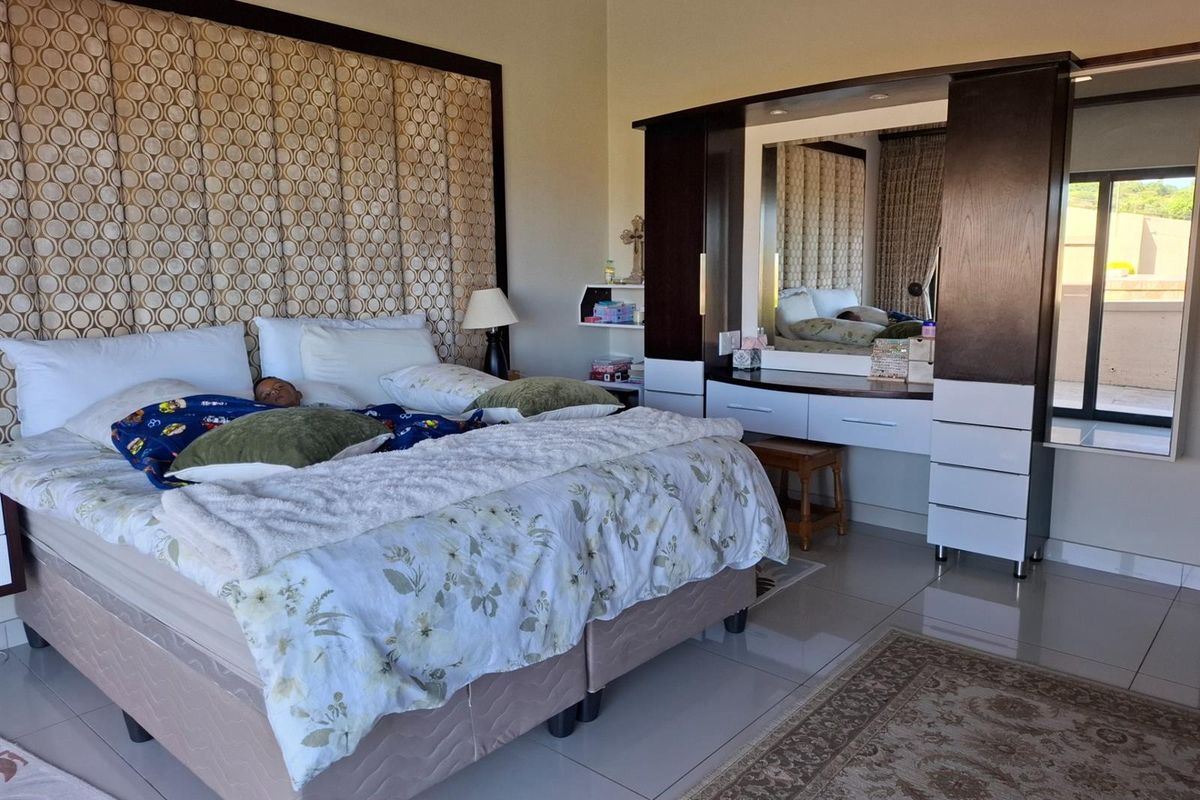Spacious bedroom featuring a large upholstered feature headboard and integrated built-in vanity unit with mirror and storage drawers.