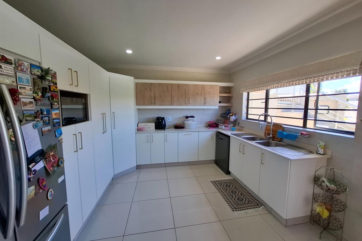 A functional kitchen featuring white cabinetry, wood-tone upper cabinets, tiled flooring, a double-basin sink, and integrated dishwasher space.