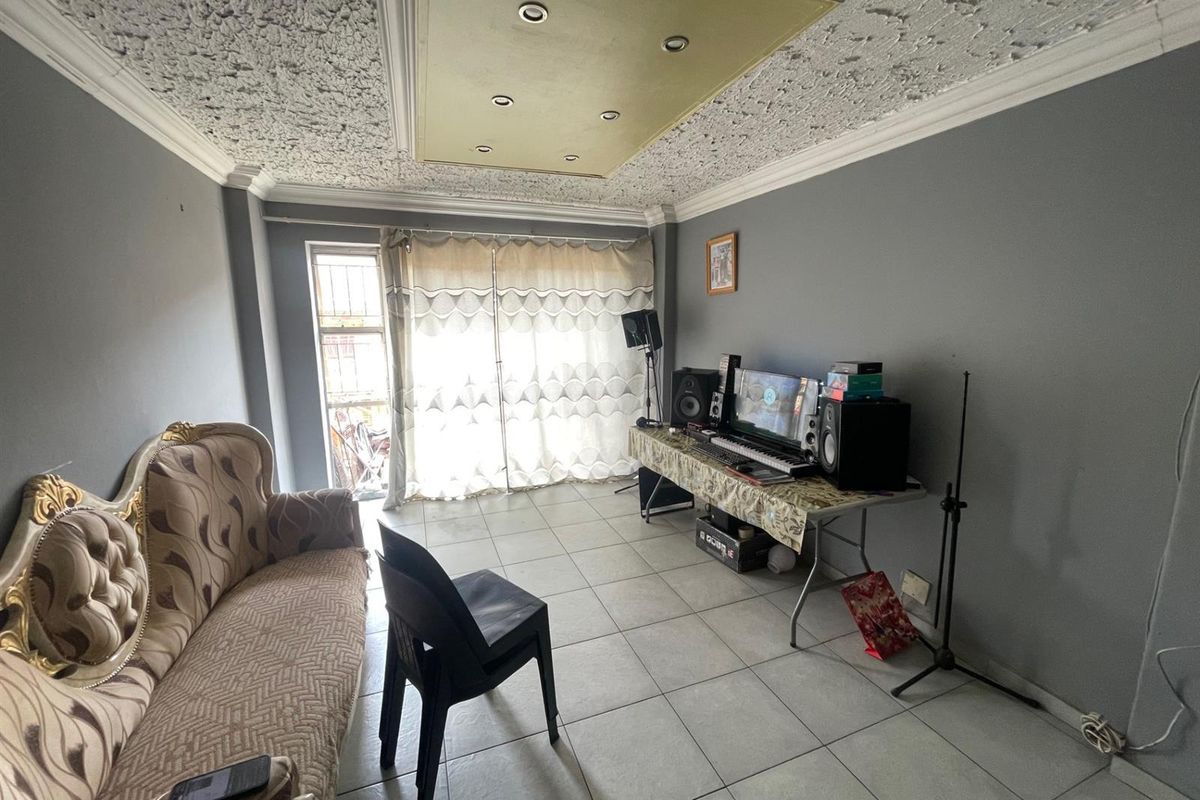 A living room featuring tiled flooring, a textured ceiling with recessed lighting, and a sliding glass door providing access to the exterior.