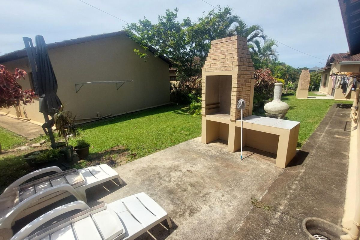 A private rear garden area featuring a built-in brick braai and concrete patio space, ideal for outdoor entertaining.