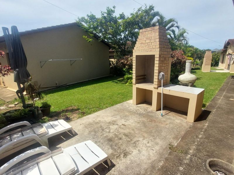 A private rear garden area featuring a built-in brick braai and concrete patio space, ideal for outdoor entertaining.