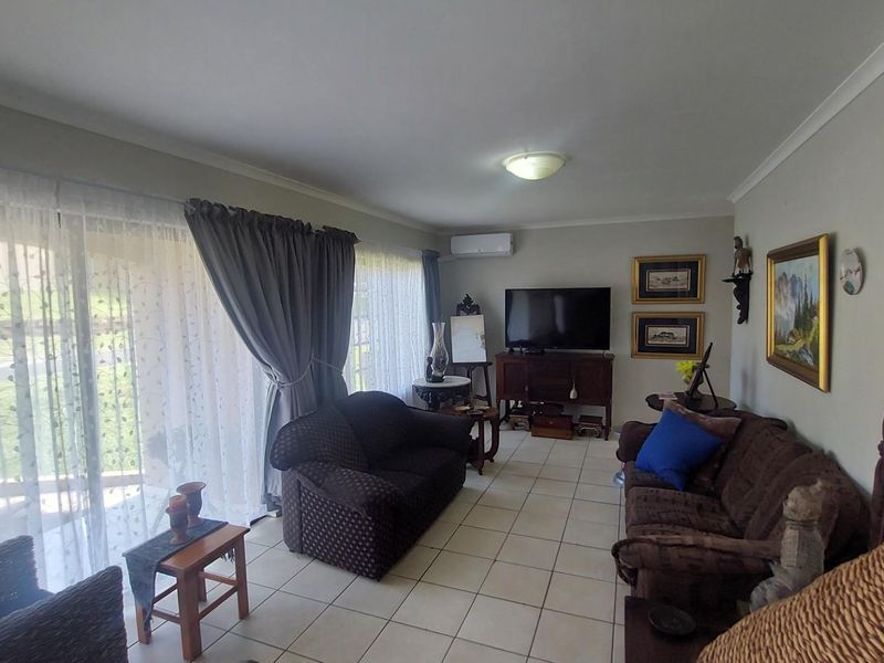 A spacious living room featuring tiled flooring, a wall-mounted air conditioning unit, and large sliding glass doors providing access to the outdoor area.