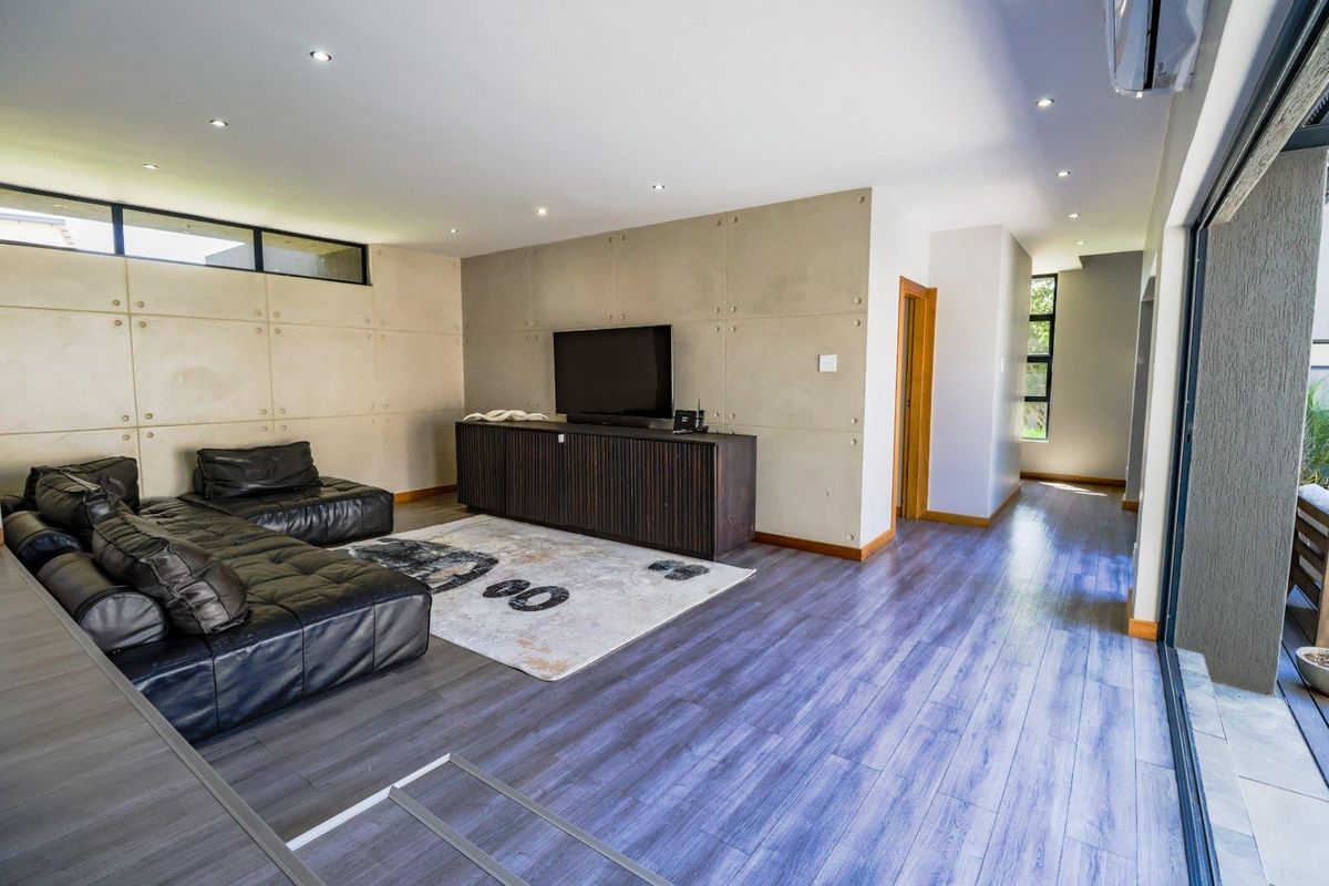 Modern living room featuring a concrete panel feature wall, laminate flooring, recessed lighting, and large sliding glass doors opening to the exterior.