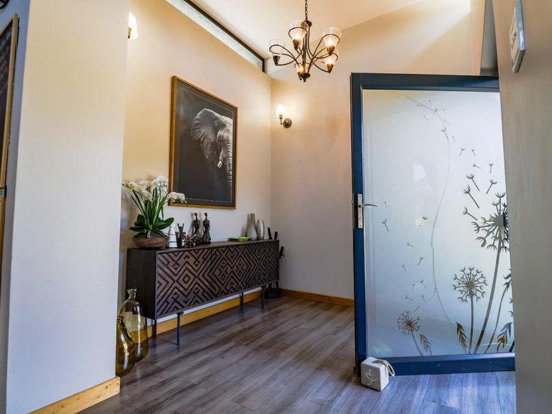 A welcoming entrance hall featuring modern laminate flooring, a decorative frosted glass door, and elegant lighting fixtures.