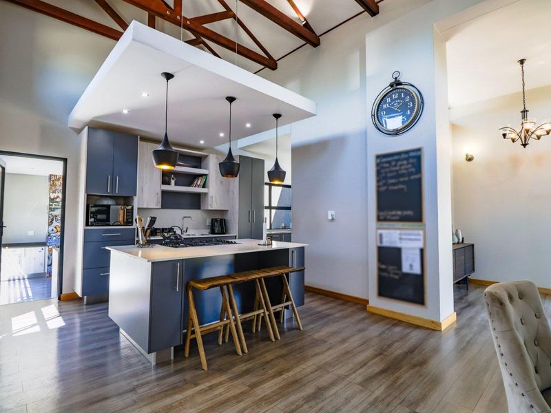 Modern kitchen featuring a central island with gas hob, sleek cabinetry, and striking exposed timber roof trusses, creating an open and airy atmosphere.