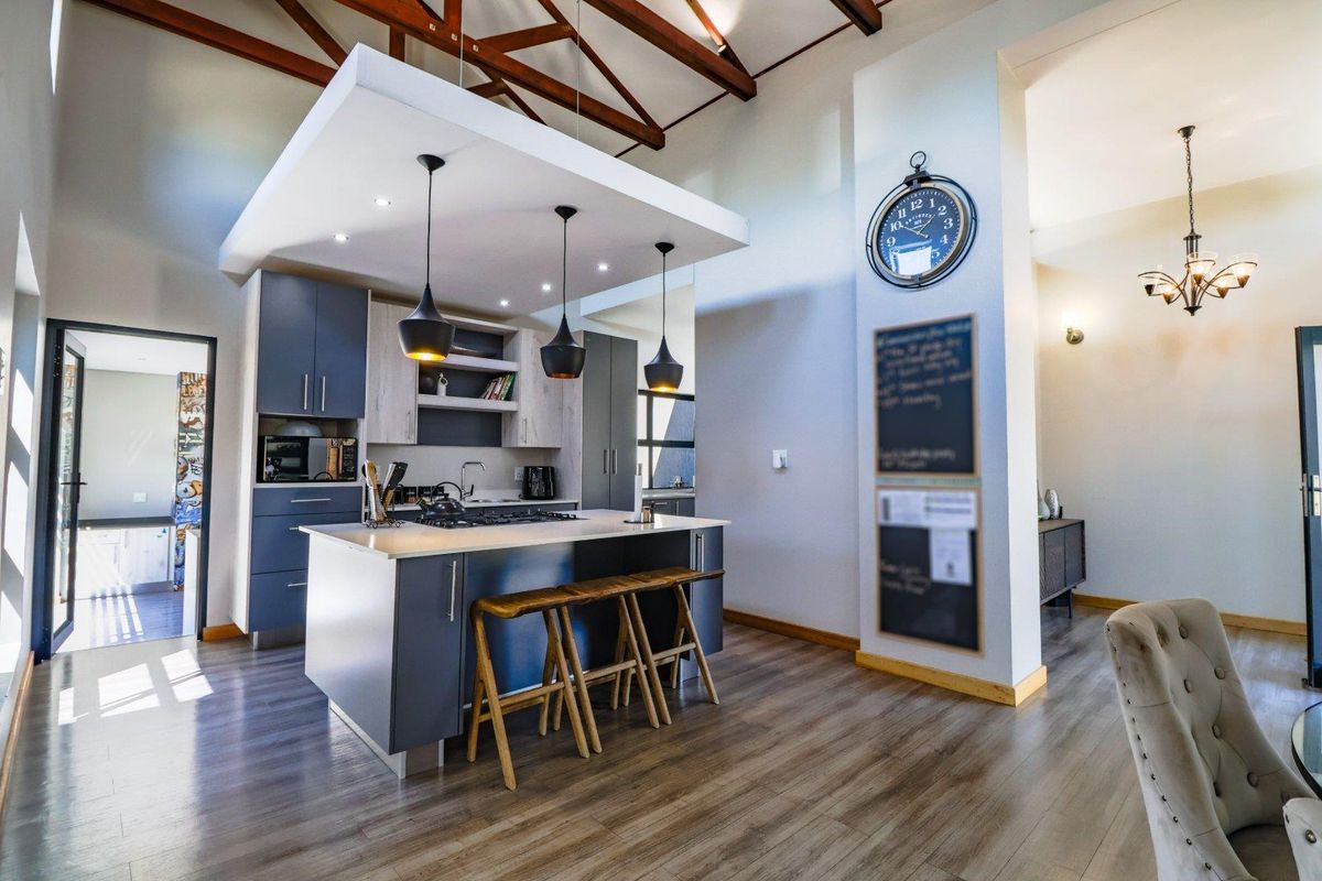 Modern kitchen featuring a central island with gas hob, sleek cabinetry, and striking exposed timber roof trusses, creating an open and airy atmosphere.