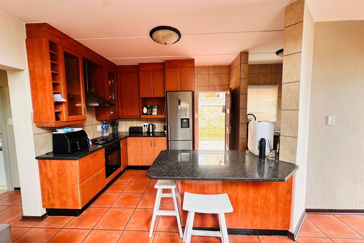A functional kitchen featuring wood-veneer cabinetry, granite countertops, a breakfast nook, and direct access to an outdoor area.