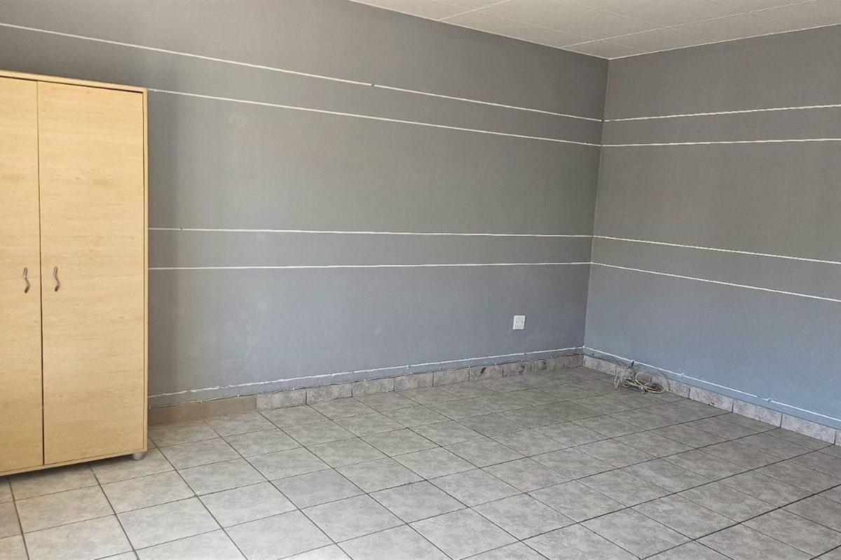 An empty bedroom featuring grey painted walls with decorative white lines and tiled flooring, requiring minor cosmetic updates.
