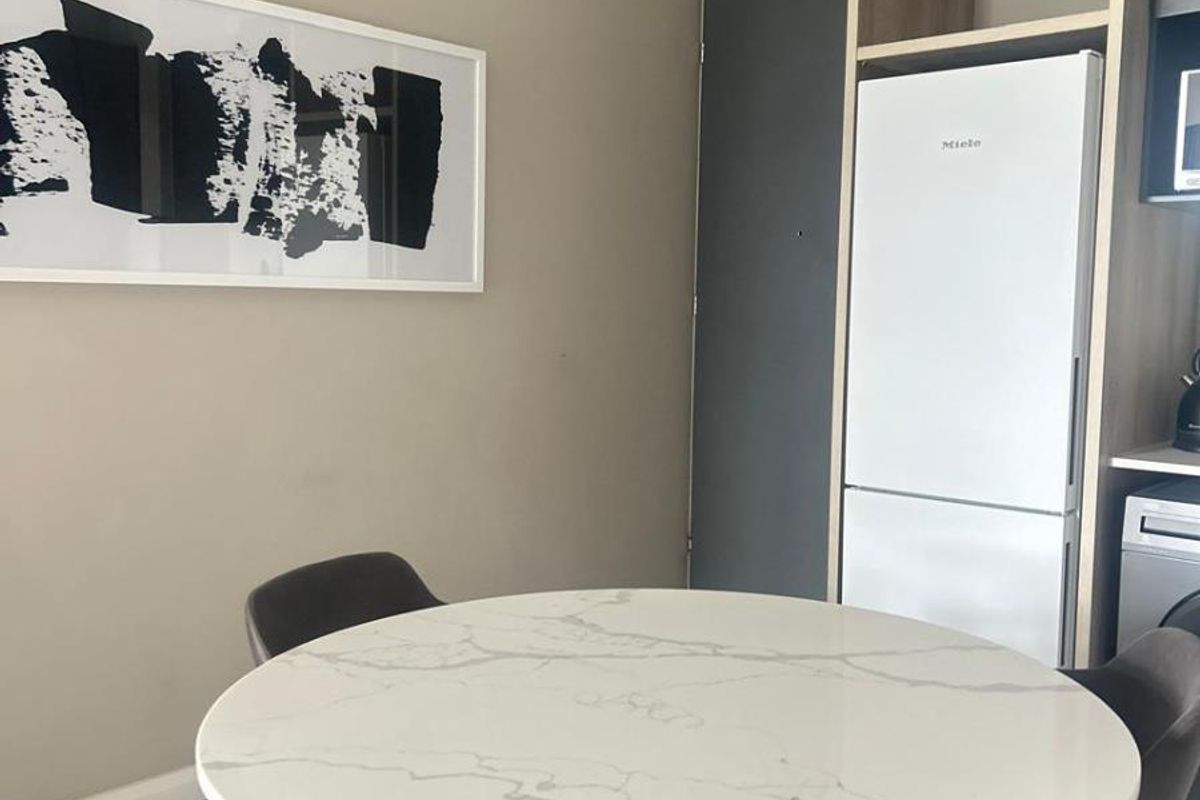 A modern kitchen area featuring integrated cabinetry, a built-in Miele refrigerator, and sleek tiled flooring in a contemporary apartment setting.