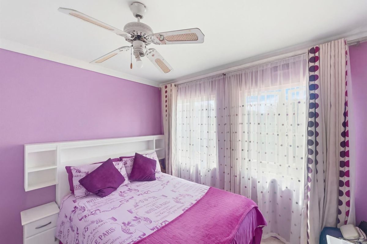 A bedroom featuring a built-in headboard with integrated shelving and a ceiling fan.