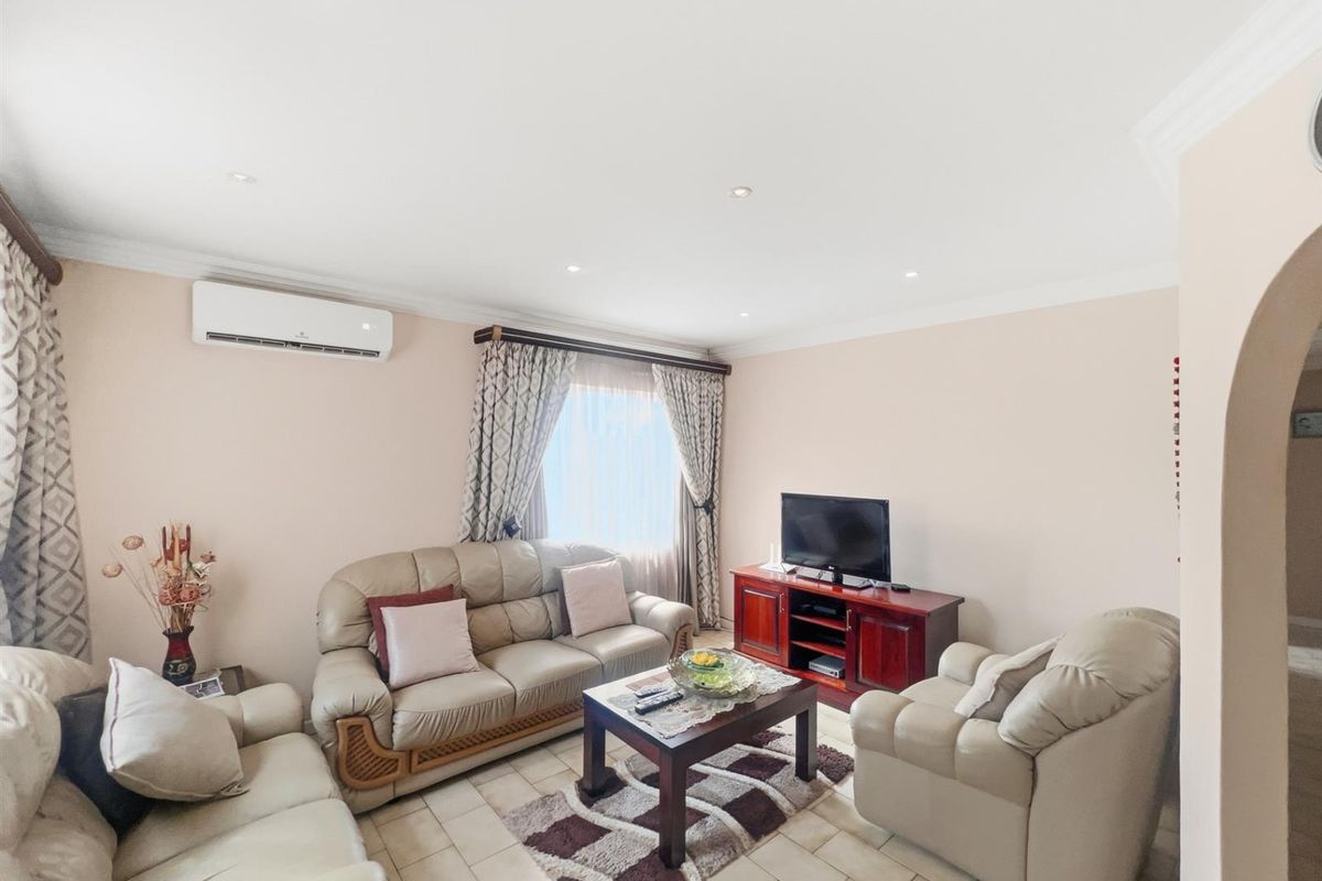 A comfortable living room featuring tiled flooring, recessed ceiling lighting, and a wall-mounted air conditioning unit.
