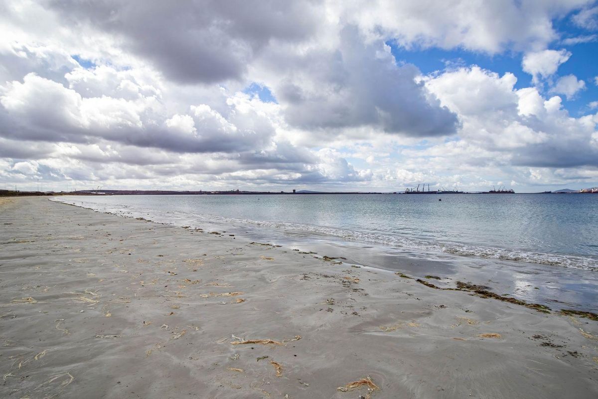 A scenic view of the sandy coastline and calm ocean waters, showcasing the natural landscape of the vacant residential property.