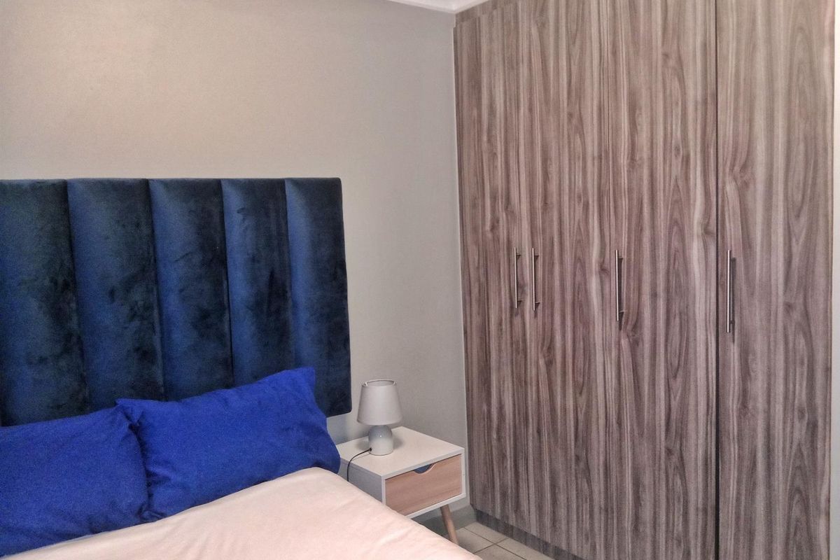A well-maintained bedroom featuring modern wood-grain built-in wardrobes and neutral tiled flooring.