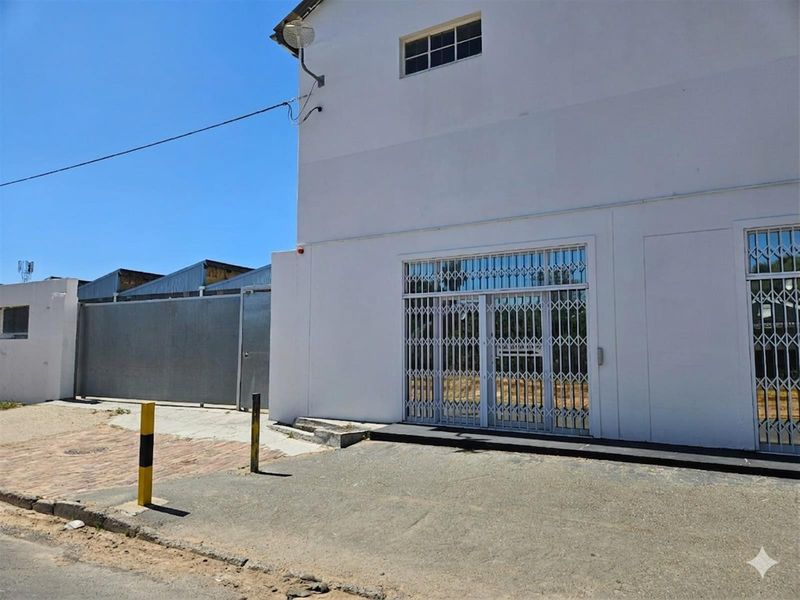 Exterior view of the office building entrance featuring security gates, paved access area, and metal perimeter fencing.