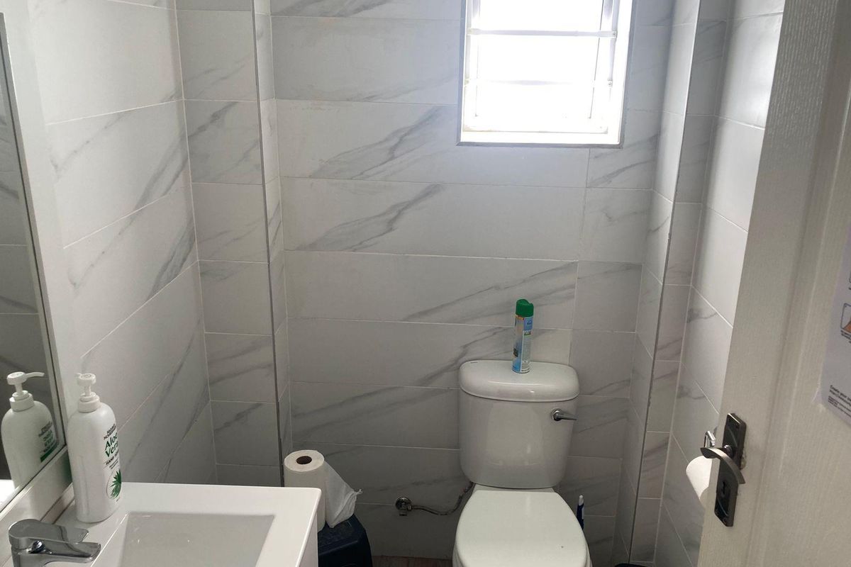 A compact, modern bathroom featuring marble-look wall tiles, a white vanity basin, and a standard toilet.