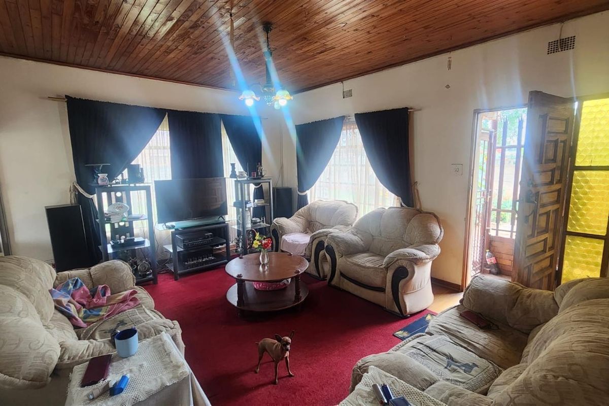 A living room featuring a timber-clad ceiling and red carpeting, providing a traditional layout with direct access to an exterior entrance.
