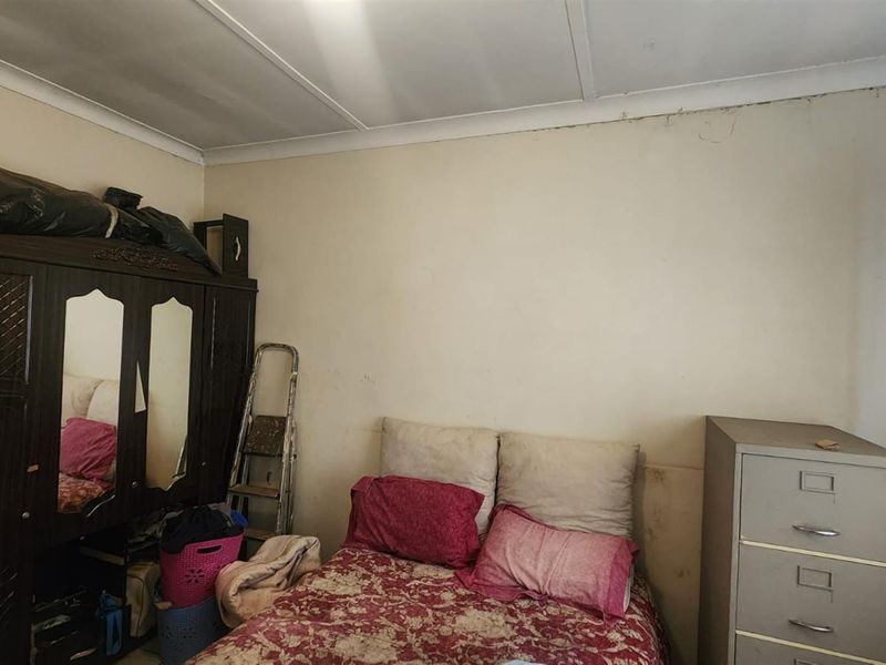 A bedroom featuring standard finishes, requiring cosmetic updates to the walls and ceiling to improve the overall aesthetic.