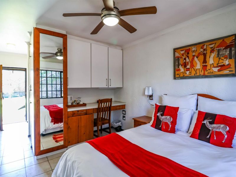 A bedroom featuring built-in cabinetry, a desk area, a ceiling fan, and tiled flooring, with direct access to an outdoor area.