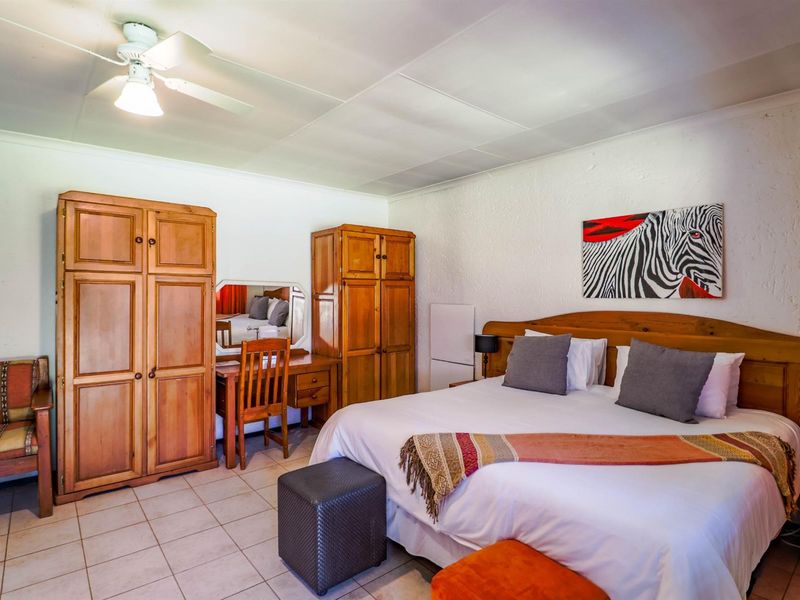 A bedroom featuring tiled flooring and a ceiling fan, providing a functional space with neutral wall finishes.