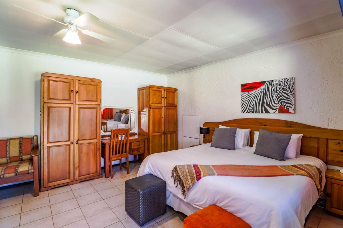 A bedroom featuring tiled flooring and a ceiling fan, providing a functional space with neutral wall finishes.