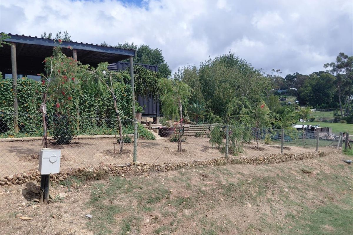 A view of the rear garden area featuring a covered patio, established greenery, and a wire fence boundary.