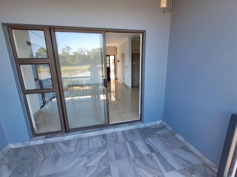 A covered patio area featuring grey tiled flooring and sliding glass doors providing access to the interior living space.