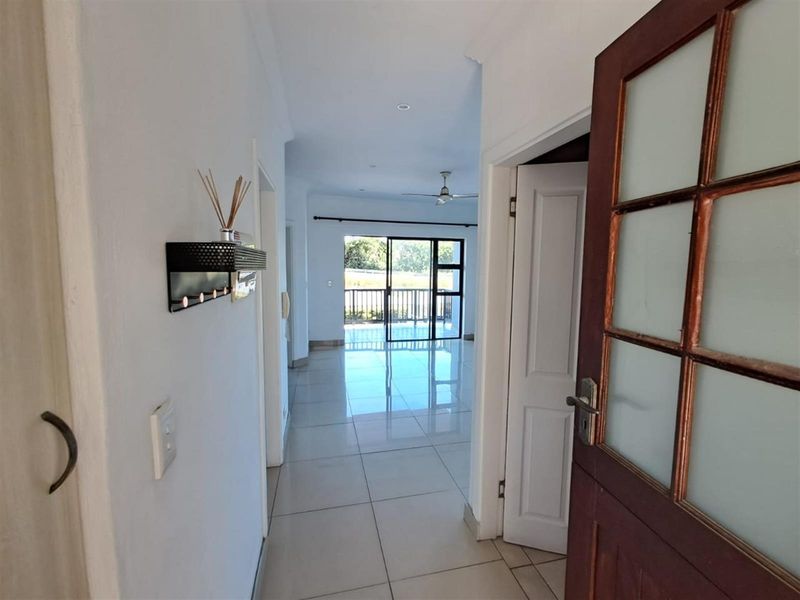 View from the entrance hallway looking through to the open plan living area and balcony with tiled flooring throughout.