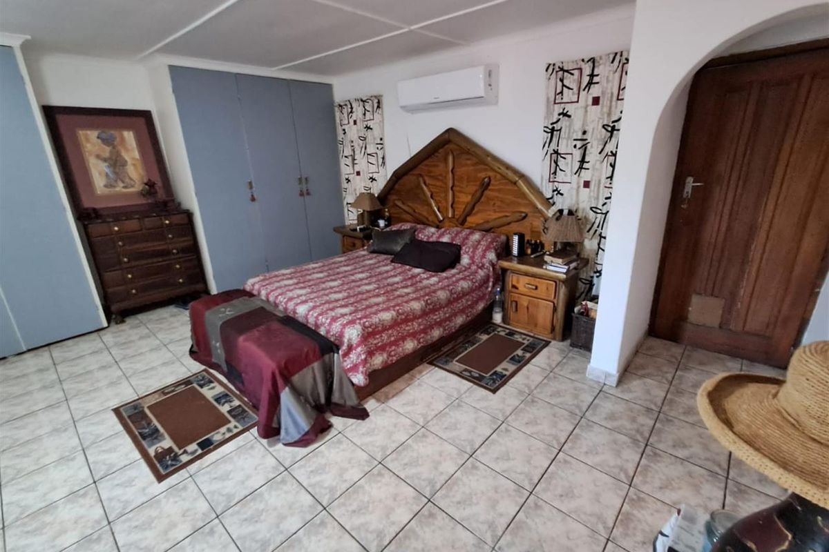 A spacious bedroom featuring tiled flooring, built-in cupboards, and a wall-mounted air conditioning unit.