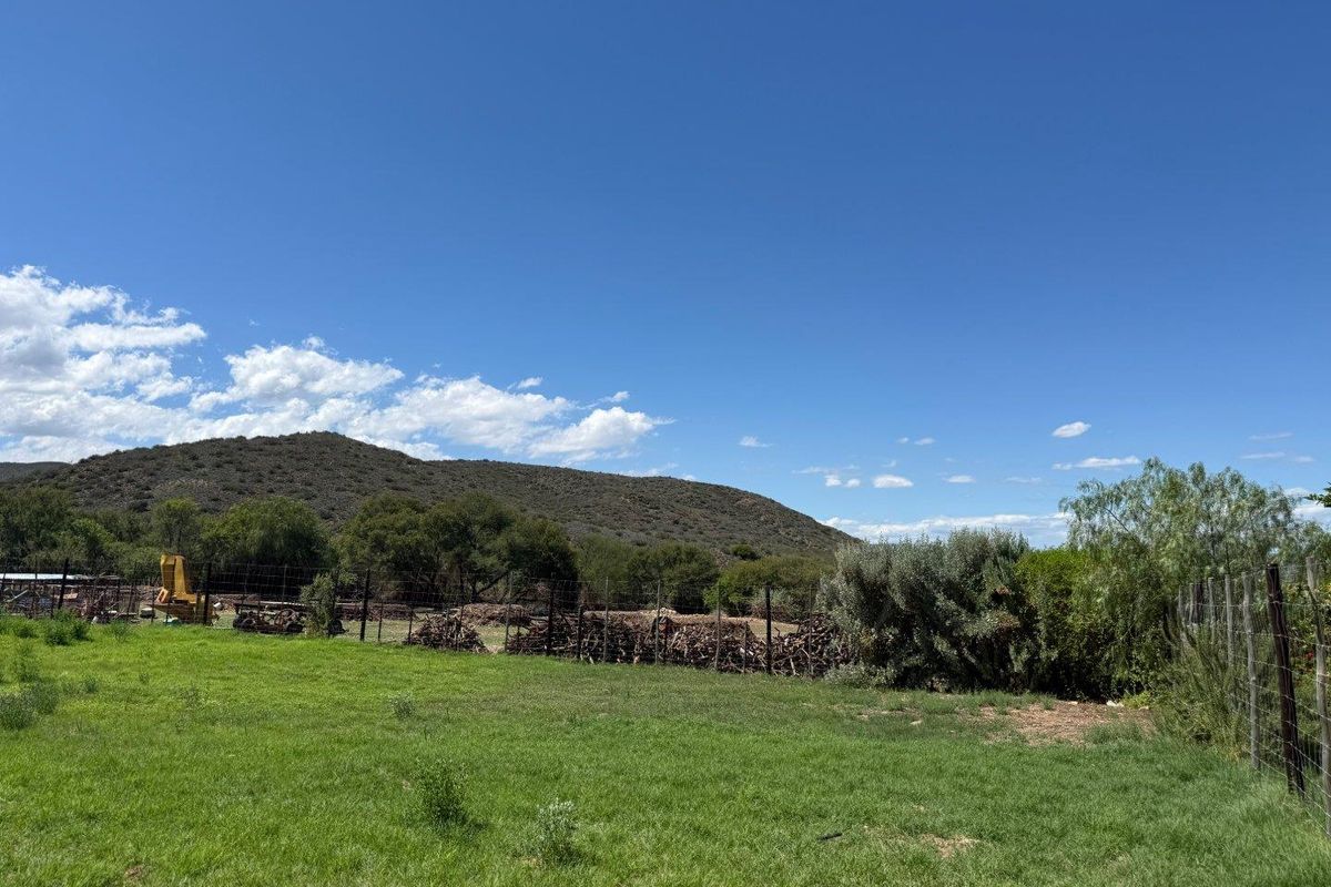 Expansive open farm land featuring natural grass, perimeter wire fencing, and scenic mountain views in a rural setting.