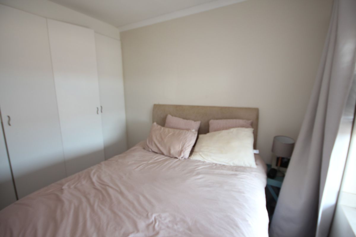 A bedroom featuring built-in wardrobes with white cabinetry and neutral wall finishes.