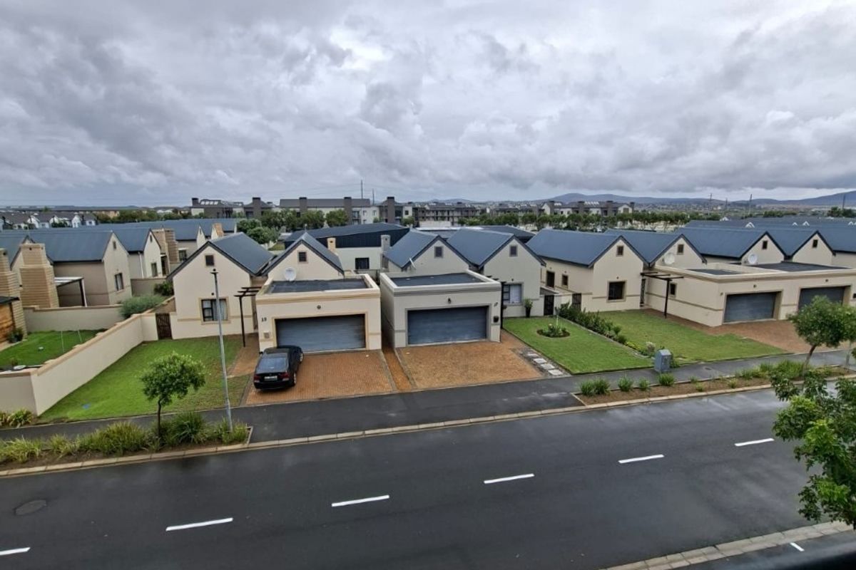 An elevated view overlooking a residential street with a row of modern suburban houses featuring pitched roofs and paved driveways.