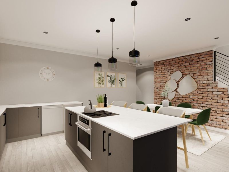 Modern open-plan kitchen and dining area featuring a central island, built-in appliances, exposed brick feature wall, and staircase access.