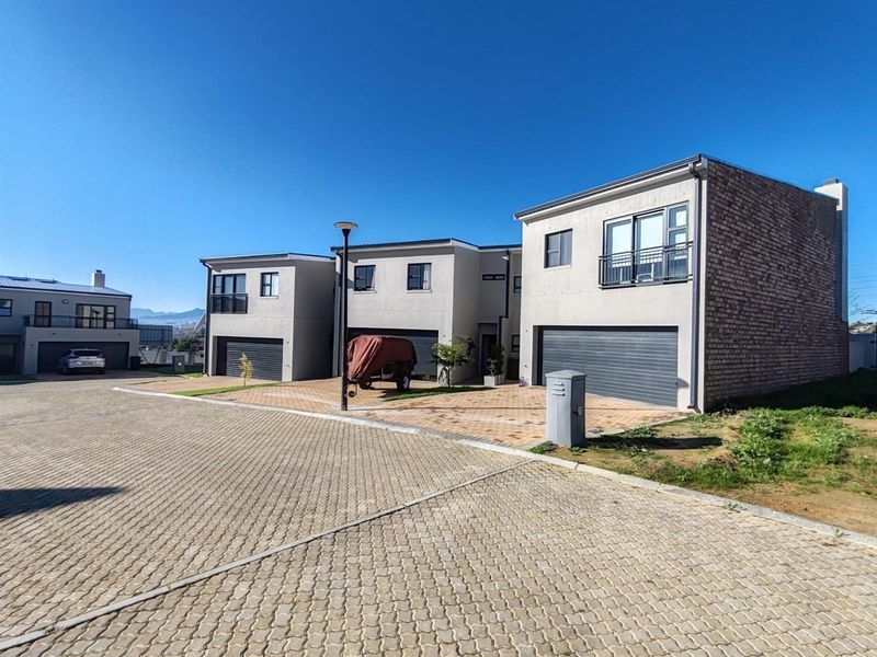 Modern multi-unit residential property featuring paved driveways, double garages, and upper-level balconies with a clean, contemporary architectural design.