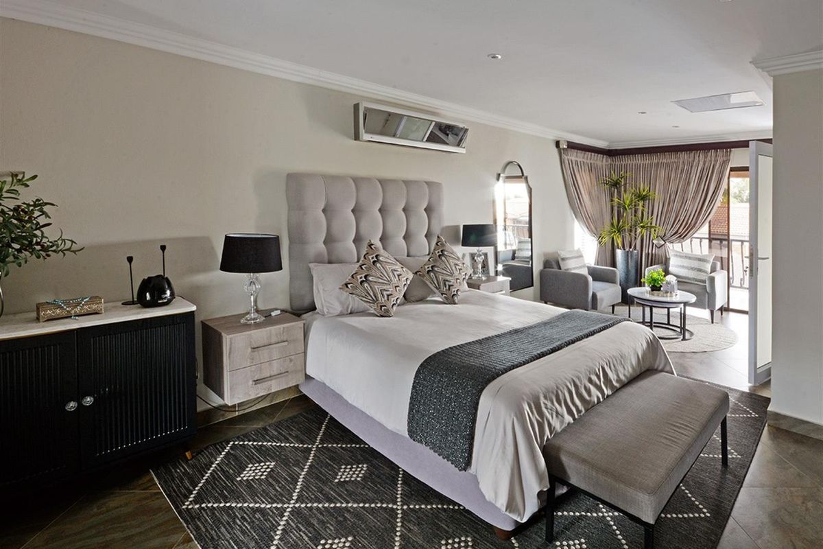 Spacious bedroom featuring a built-in air conditioning unit, recessed ceiling lighting, and direct access to a private balcony through glass doors.