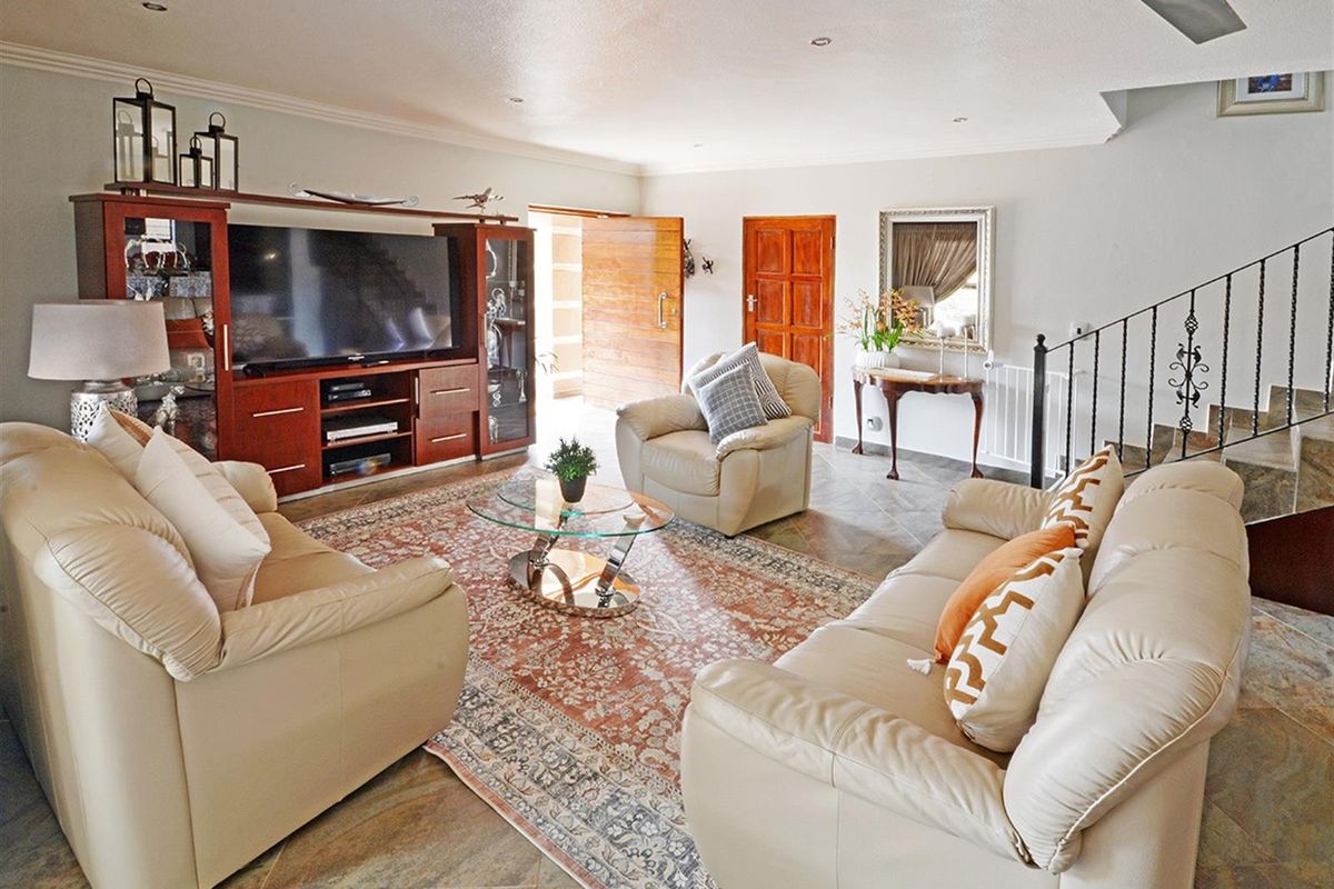 Spacious living room featuring tiled flooring, recessed ceiling lighting, a ceiling fan, and a staircase with decorative wrought iron railings.