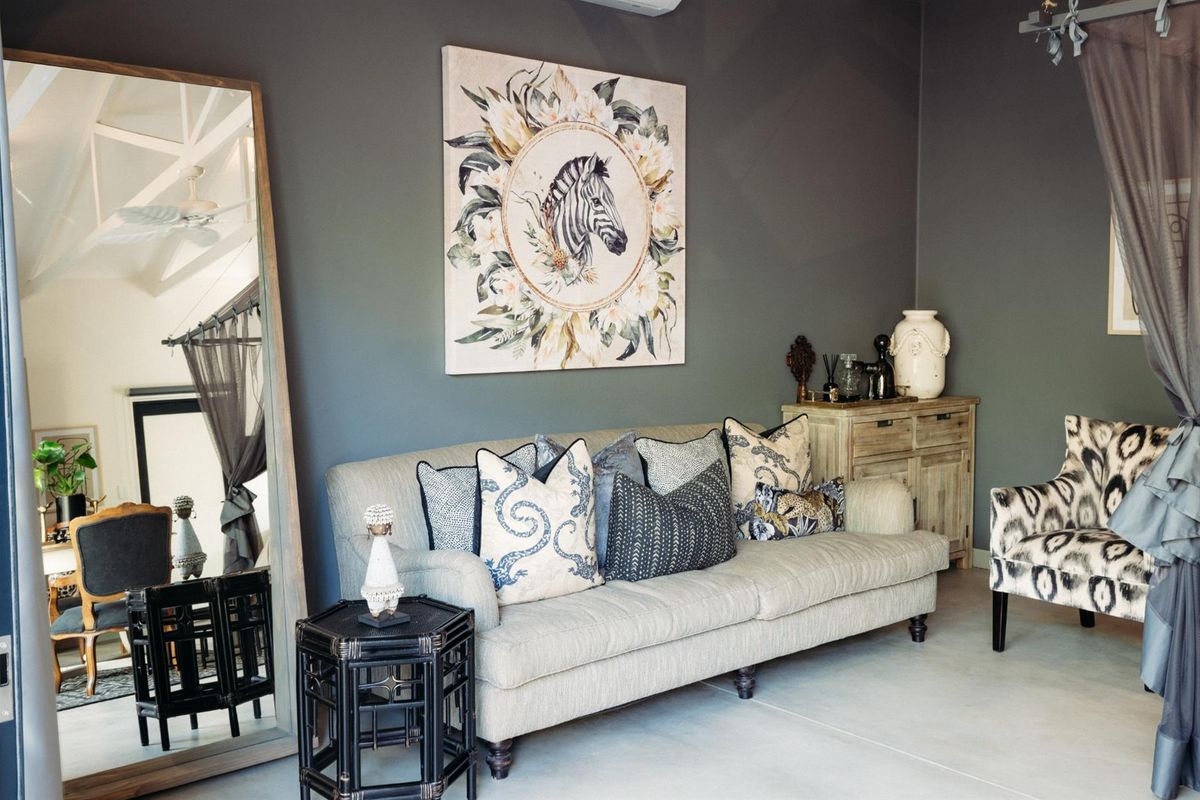 A well-appointed living room featuring polished concrete flooring, dark grey feature walls, and a vaulted ceiling with a ceiling fan.