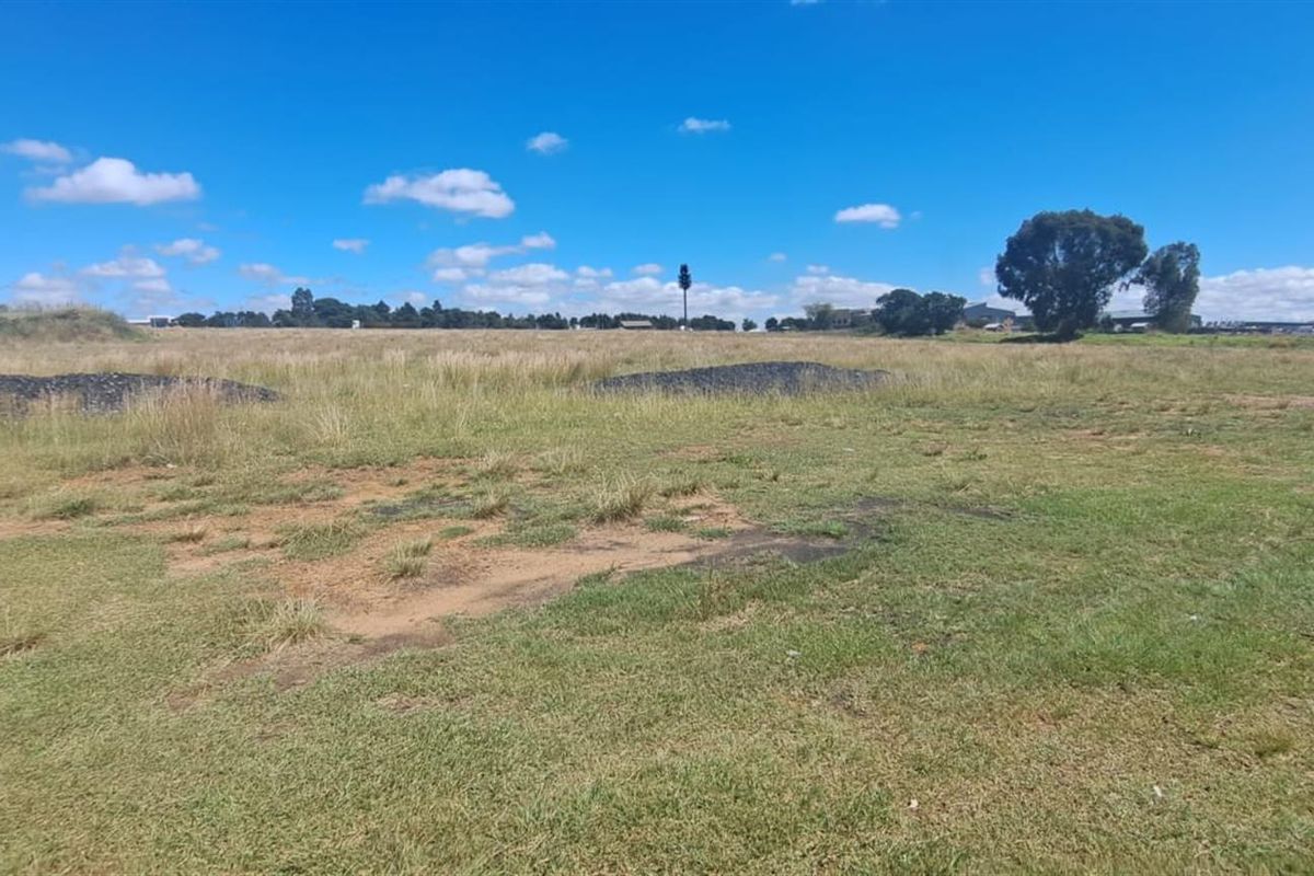 A wide-angle view of a vacant agricultural land plot featuring open grassy terrain and clear horizon lines.