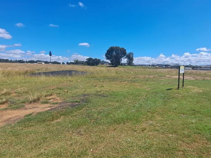 A wide-angle view of a vacant agricultural land plot featuring open grassy terrain and a clear horizon line.