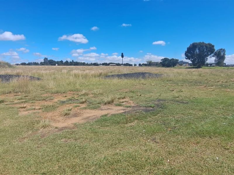 A wide-angle view of a vacant agricultural land plot featuring open grassy terrain and clear horizon lines.